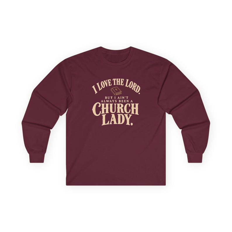 Maroon long-sleeve shirt with cream vintage lettering and a small gold Bible: I LOVE THE LORD. BUT I AIN’T ALWAYS BEEN A CHURCH LADY.
